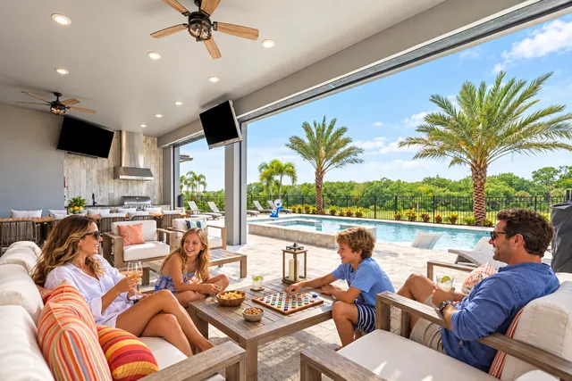 Family playing a board game on a covered patio beside the pool