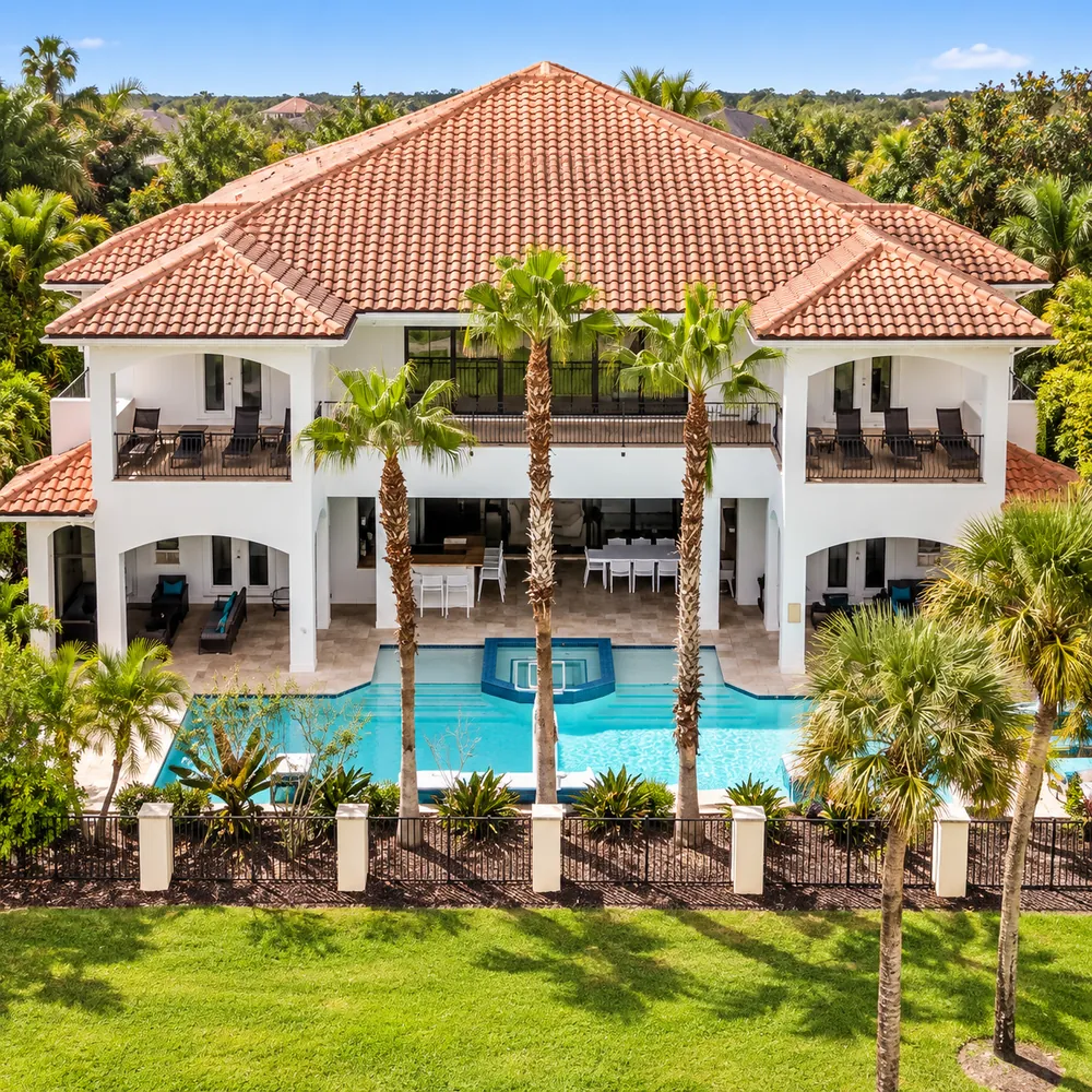 Mediterranean-style luxury vacation home with a terracotta roof, palms and private pool
